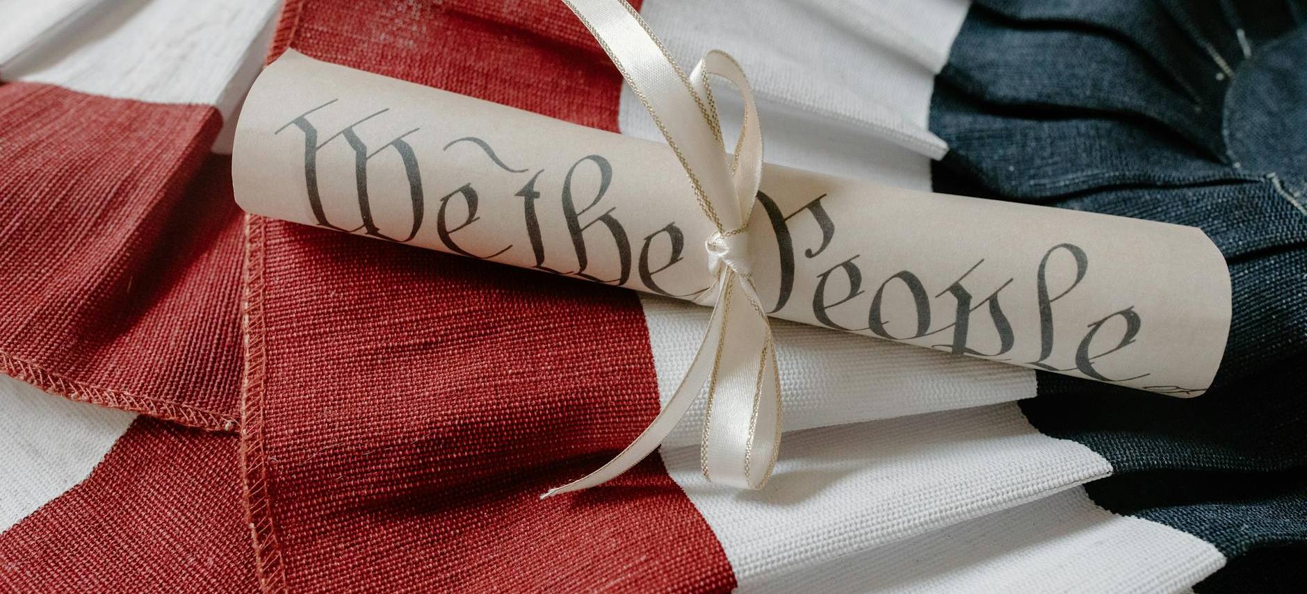 The U.S. Constitution rolled and tied with ribbon, reading We the People